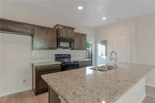 a kitchen with kitchen island a sink a stove and wooden cabinets