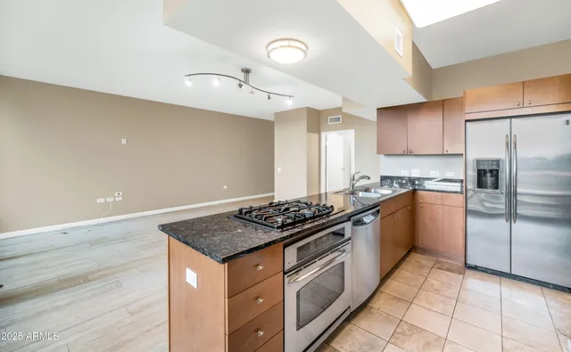 a kitchen with granite countertop stainless steel appliances a stove top oven a sink and cabinets