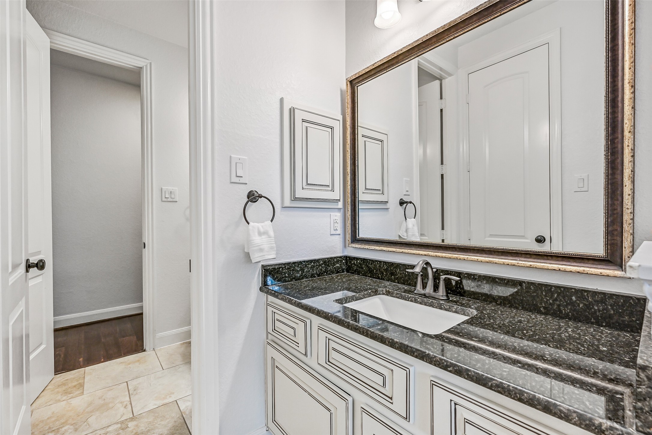 1008 Point Isabel Lane Friendswood, TX 77546 - Photo 25 of 50 The en suite begins with a private vanity featuring granite countertops, an undermount rectangular basin sink, a framed mirror, and inked cabinetry, offering a separate prep space from the rest of the bath.
