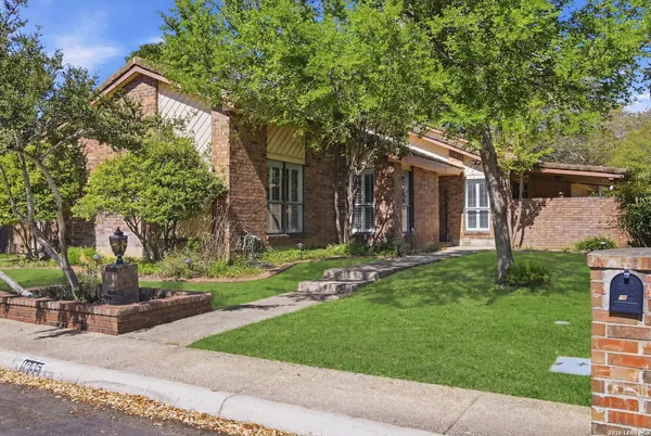 a front view of a house with a garden and tree