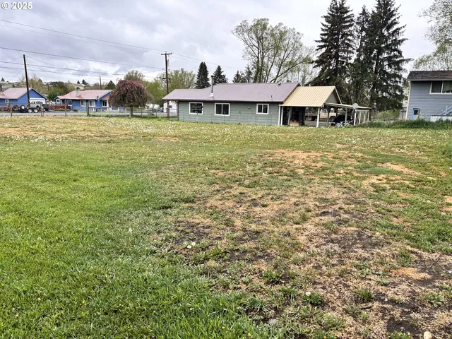 a view of a large pool with lawn chairs under an umbrella