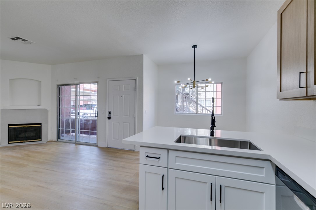 4730 East Craig Road, Unit 1085 Las Vegas, NV 89115 - Photo 9 of 23 A sleek island with a modern sink anchors this open-concept living space, featuring a cozy fireplace and access to outdoor areas.