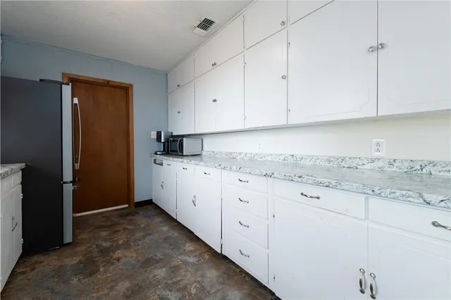 a kitchen with granite countertop white cabinets and refrigerator