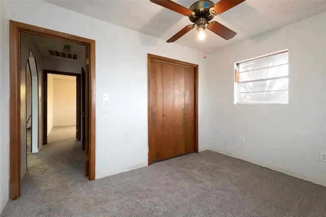 an empty room that has a window and a ceiling fan