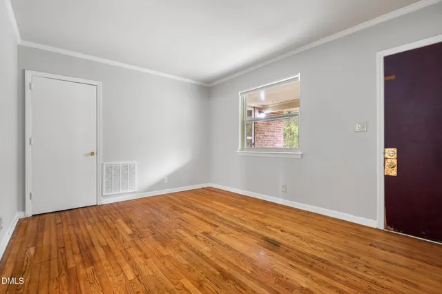 a view of an empty room with wooden floor and a window