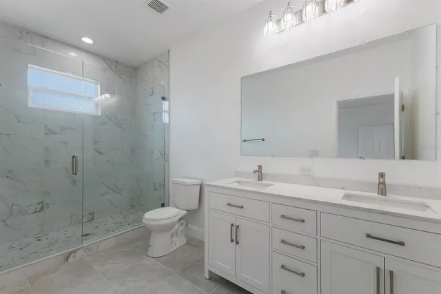 a bathroom with a double vanity sink toilet and shower