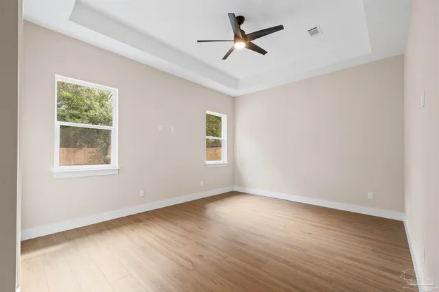 an empty room with wooden floor and windows