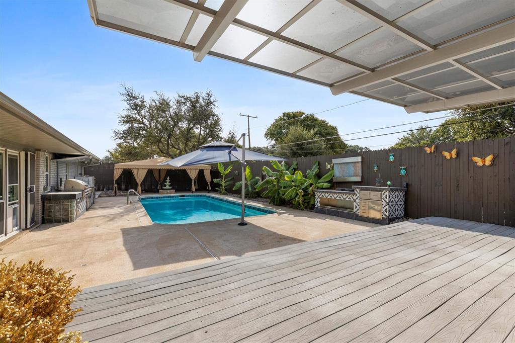 4436 Thunder Road Dallas, TX 75244 - Photo 28 of 33 Expansive outdoor area featuring a swimming pool, wood deck, covered patio, built-in outdoor kitchen, and privacy fencing