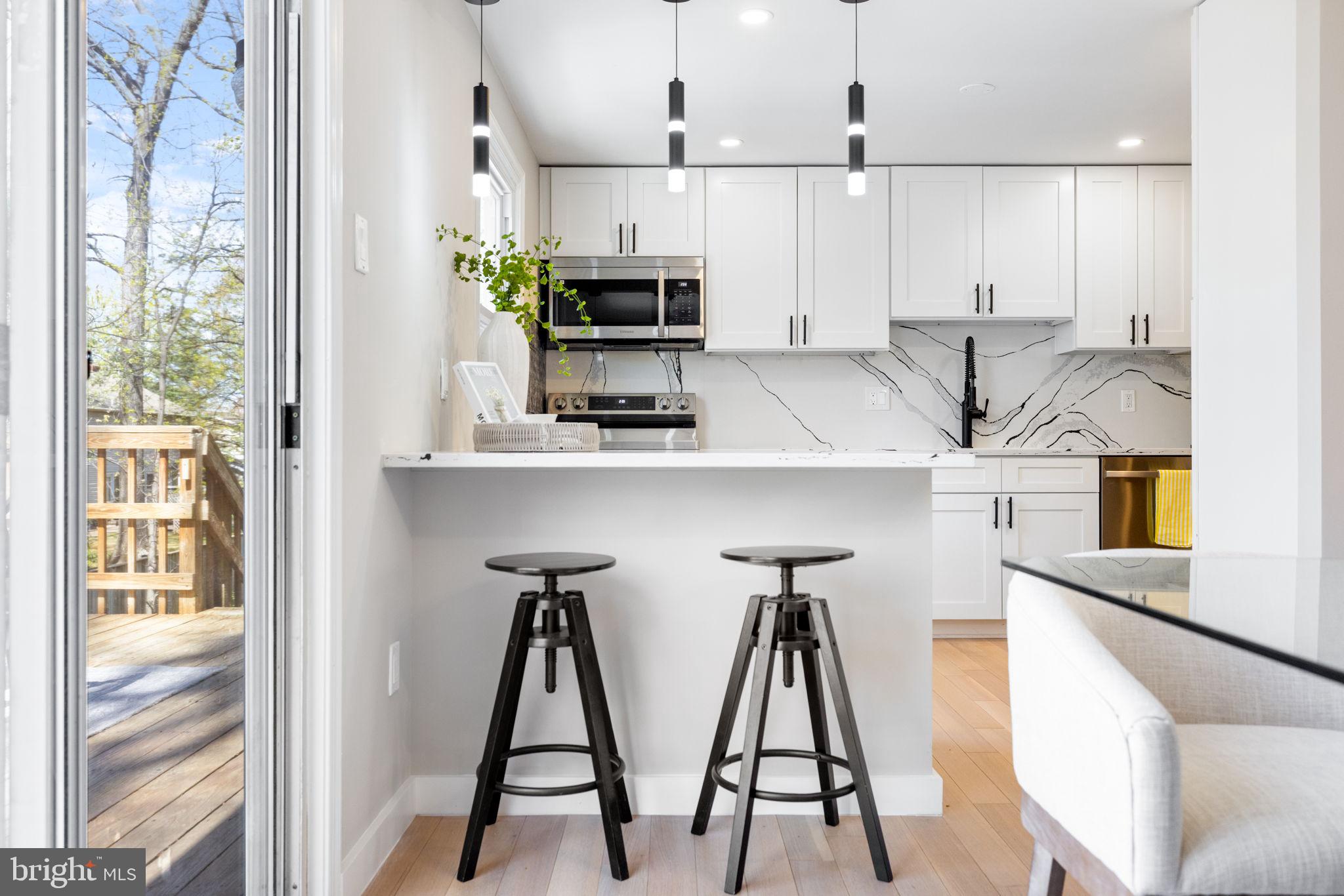 12870 Graypine Place Herndon, VA 20170 - Photo 8 of 35 a kitchen with stainless steel appliances kitchen island a table chairs in it and white cabinets