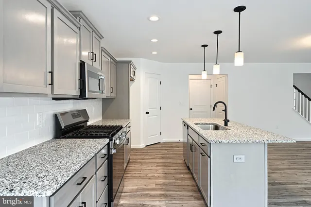 a kitchen with stainless steel appliances granite countertop a sink stove and cabinets