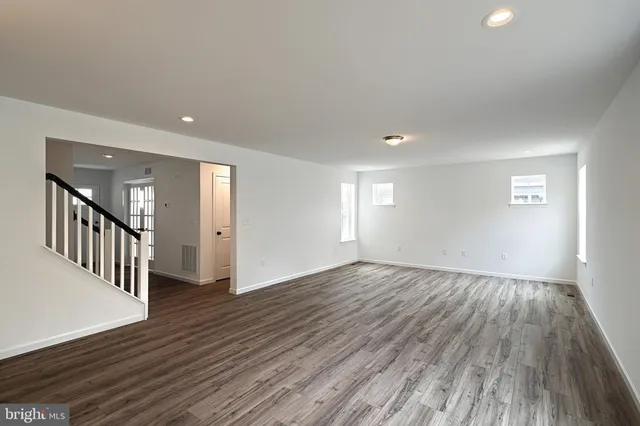 a view of an empty room with wooden floor and windows
