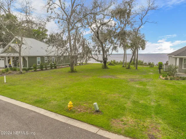 a view of a house with a big yard and large trees