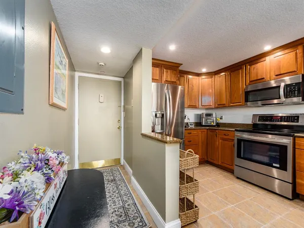 a kitchen with granite countertop stainless steel appliances a stove refrigerator sink and cabinets