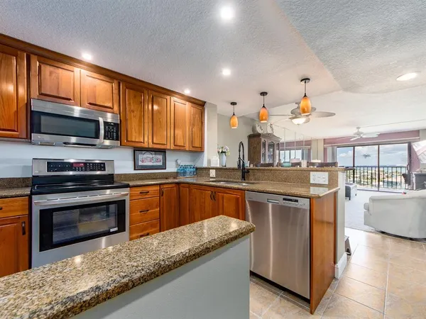 a kitchen with stainless steel appliances granite countertop a stove a sink and a microwave