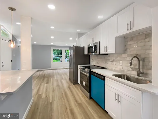 a kitchen with kitchen island white cabinets and stainless steel appliances