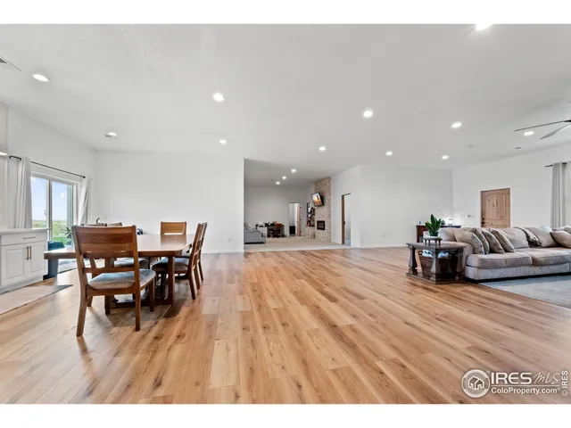 a living room with furniture and a dining table with wooden floor