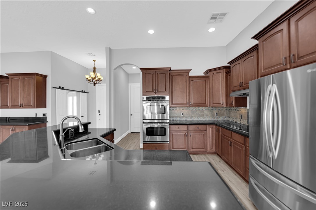 1415 Curohee Street Moapa, NV 89025 - Photo 11 of 54 Kitchen featuring stainless steel appliances, a chandelier, a barn door, recessed lighting, and light wood-style flooring