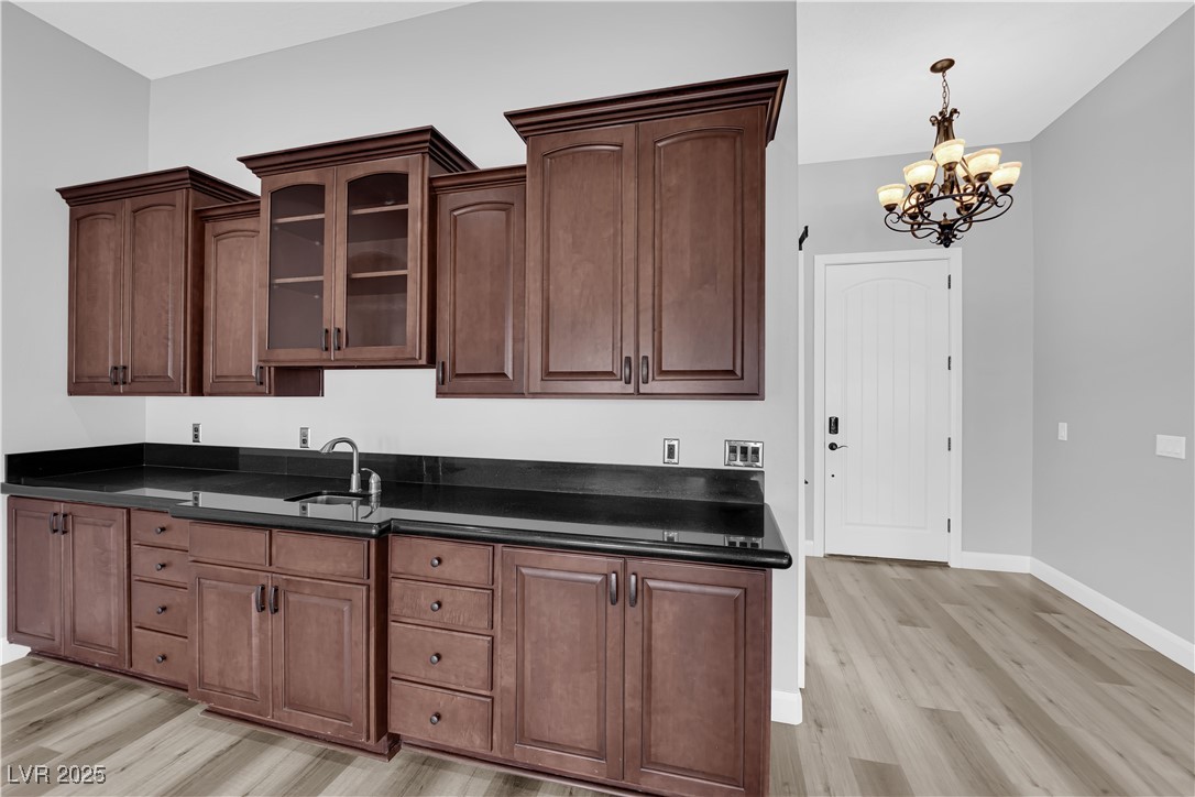 1415 Curohee Street Moapa, NV 89025 - Photo 13 of 54 Kitchen featuring a chandelier, light wood-style floors, pendant lighting, glass insert cabinets, and dark stone countertops
