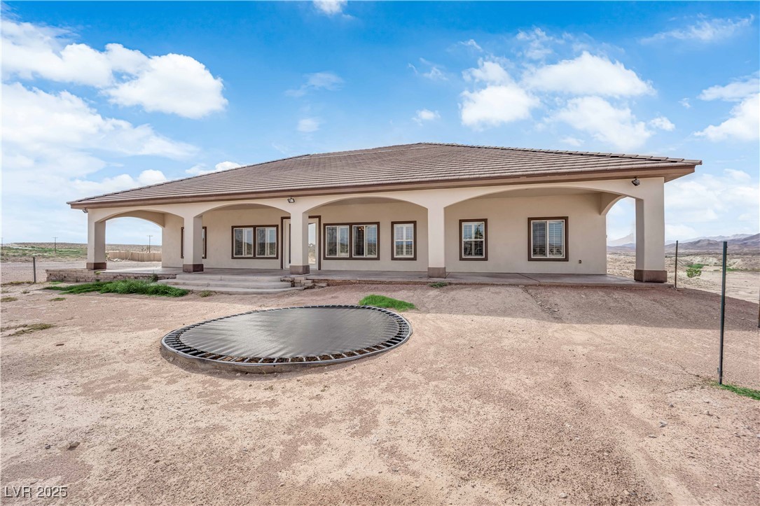 1415 Curohee Street Moapa, NV 89025 - Photo 45 of 54 Back of property with stucco siding, a tile roof, and covered porch
