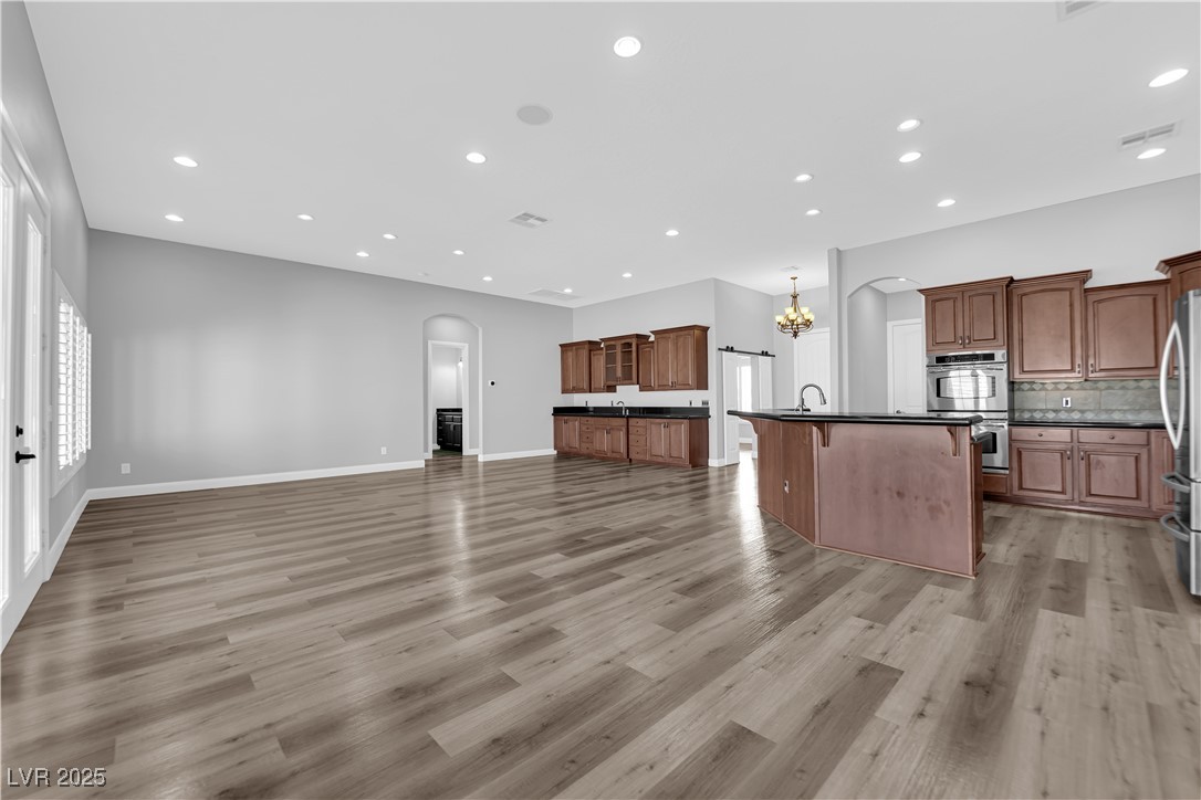 1415 Curohee Street Moapa, NV 89025 - Photo 54 of 54 Kitchen featuring arched walkways, open floor plan, recessed lighting, a kitchen bar, and light wood-type flooring