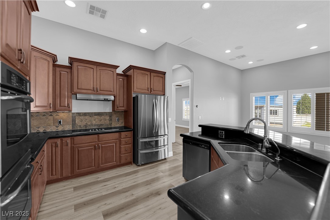 1415 Curohee Street Moapa, NV 89025 - Photo 9 of 54 Kitchen with black appliances, recessed lighting, arched walkways, tasteful backsplash, and light wood finished floors