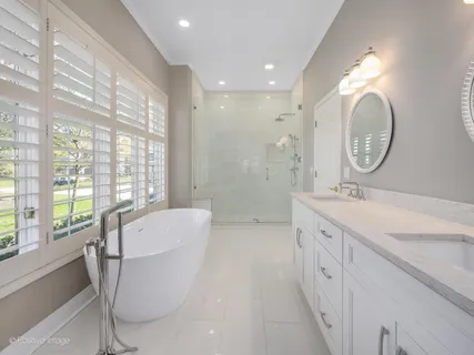 a spacious bathroom with a double vanity sink a large mirror and a bathtub