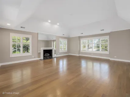 an empty room with wooden floor fireplace and windows