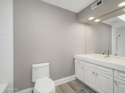 a bathroom with a toilet sink vanity and mirror