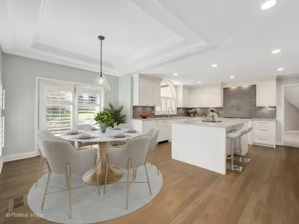 a dining room with stainless steel appliances kitchen island granite countertop a dining table chairs and a refrigerator