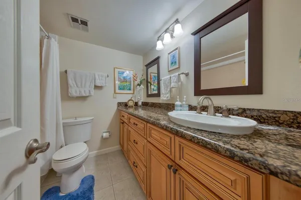 a bathroom with a granite countertop sink toilet and a mirror