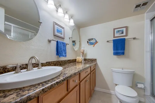 a bathroom with a granite countertop sink a toilet and a mirror