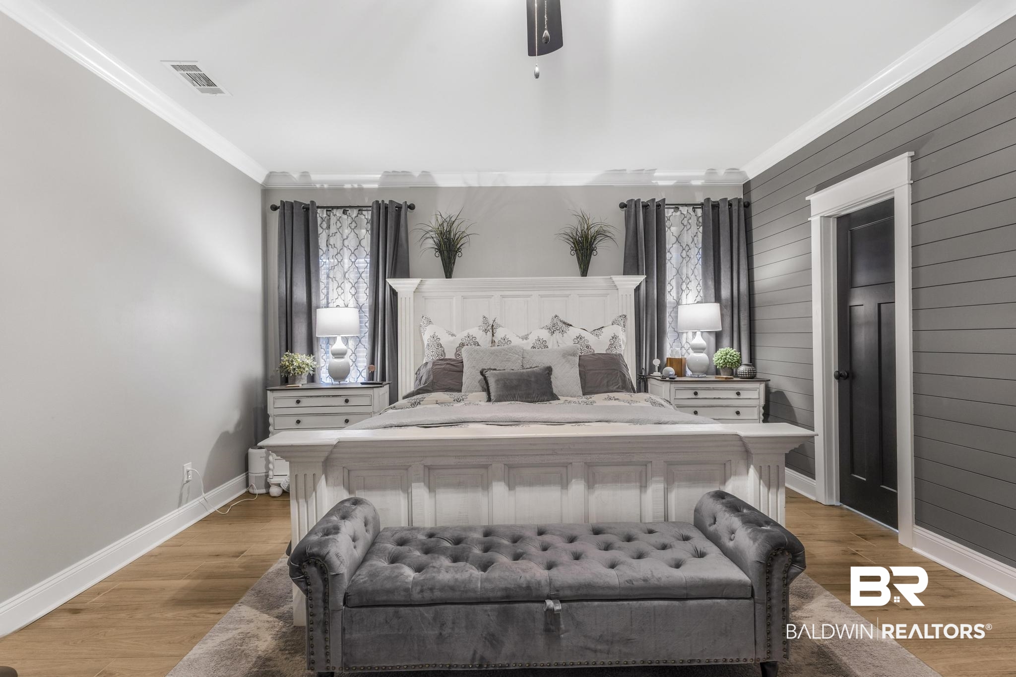 83 Caisson Trace Daphne, AL 36527 - Photo 34 of 63 Spacious bedroom featuring wood-finish flooring, a shiplap accent wall, crown molding, and a dark paneled door with white trim
