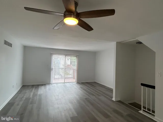 an empty room with wooden floor fan and windows