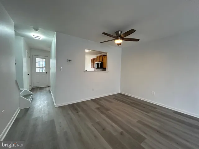 an empty room with wooden floor chandelier fan and windows