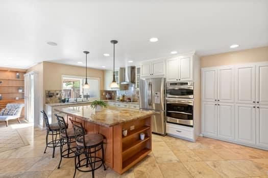 a kitchen with stainless steel appliances kitchen island granite countertop a table and chairs