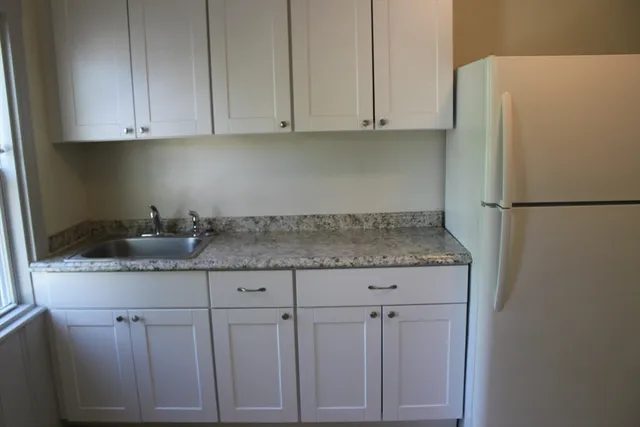 a kitchen with granite countertop white cabinets and a refrigerator