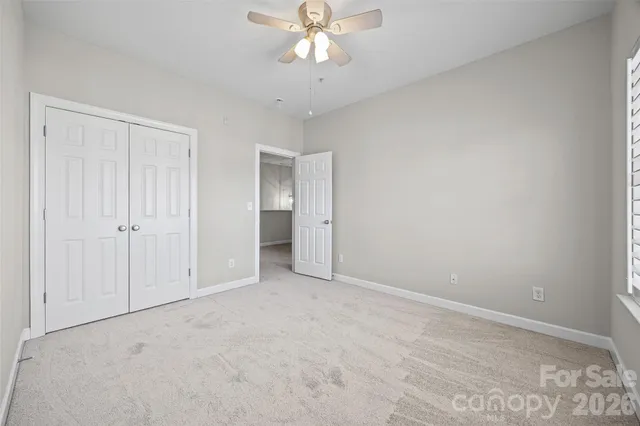 a view of an empty room and chandelier fan