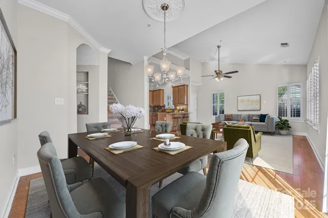 a view of a dining room and livingroom view with furniture wooden floor a chandelier