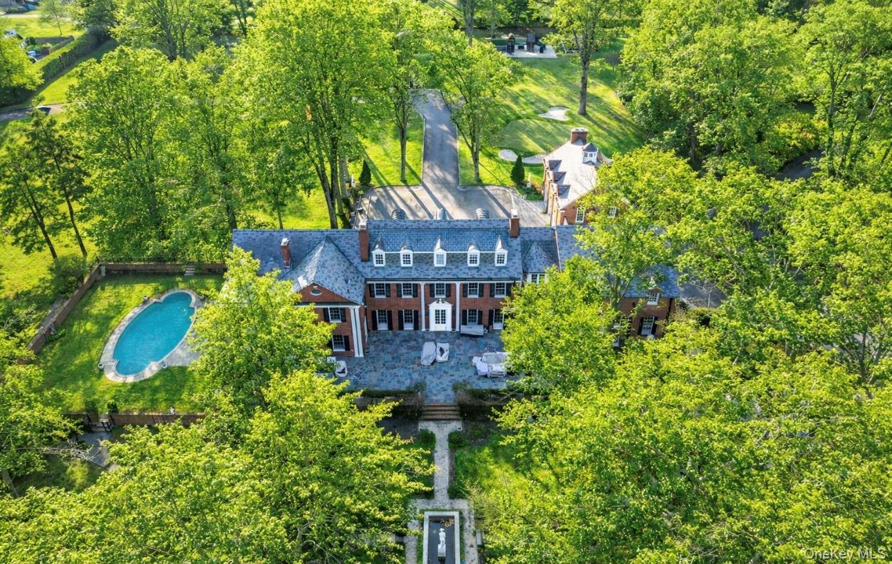 a view of a brick wall with plants and large trees