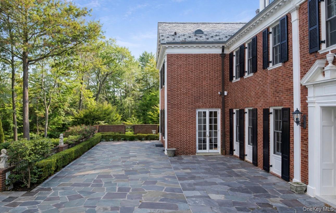 393 Mill River Road Muttontown, NY 11771 - Photo 31 of 41 a view of a brick house with many windows plants and trees
