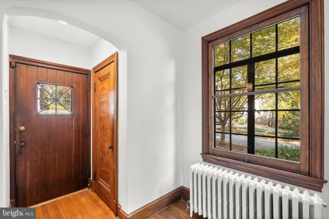a view of an empty room with wooden floor fireplace and a window