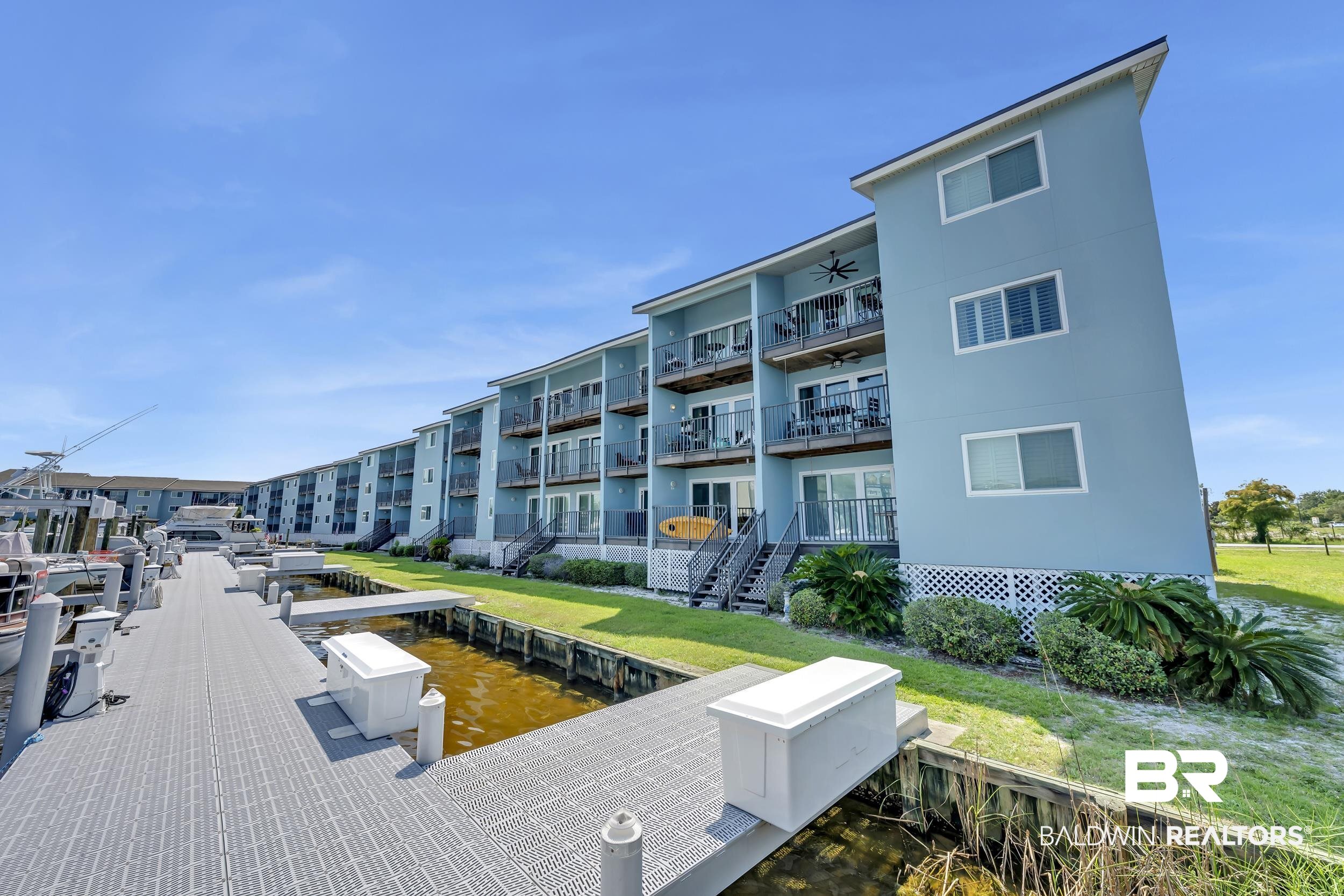 14100 River Road, Unit 211 Pensacola, FL 32507 - Photo 8 of 56 Waterfront multi-story building featuring individual balconies, ground-level patios, direct dock access, and a manicured lawn