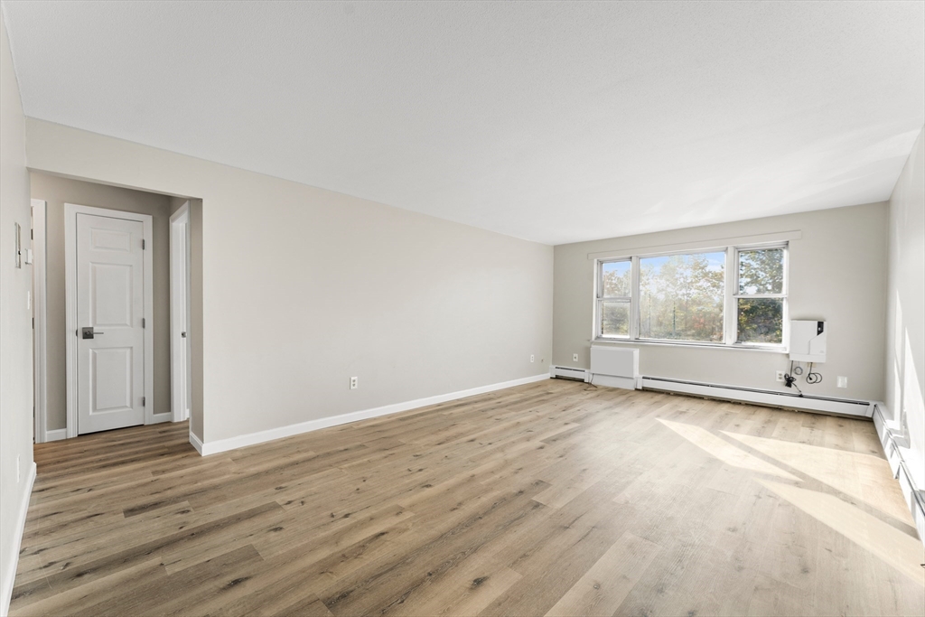 1 Colonial Drive, Unit C16 Andover, MA 01810 - Photo 7 of 32 a view of an empty room with wooden floor and a window