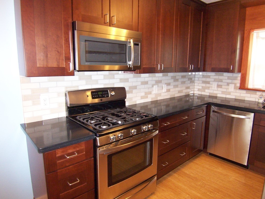 140 Lake Shore Road, Unit 1 Boston, MA 02135 - Photo 5 of 26 a kitchen with wooden cabinets and a stove top oven