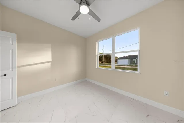 an empty room with windows and fan