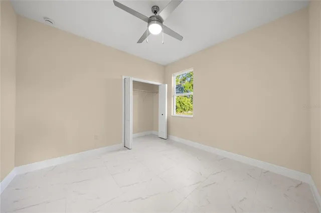 an empty room with windows and a ceiling fan