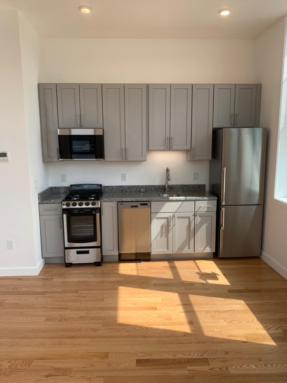 64 Market Street, Unit 401 Lynn, MA 01901 - Photo 3 of 14 a kitchen with wooden cabinets and a stainless steel appliances