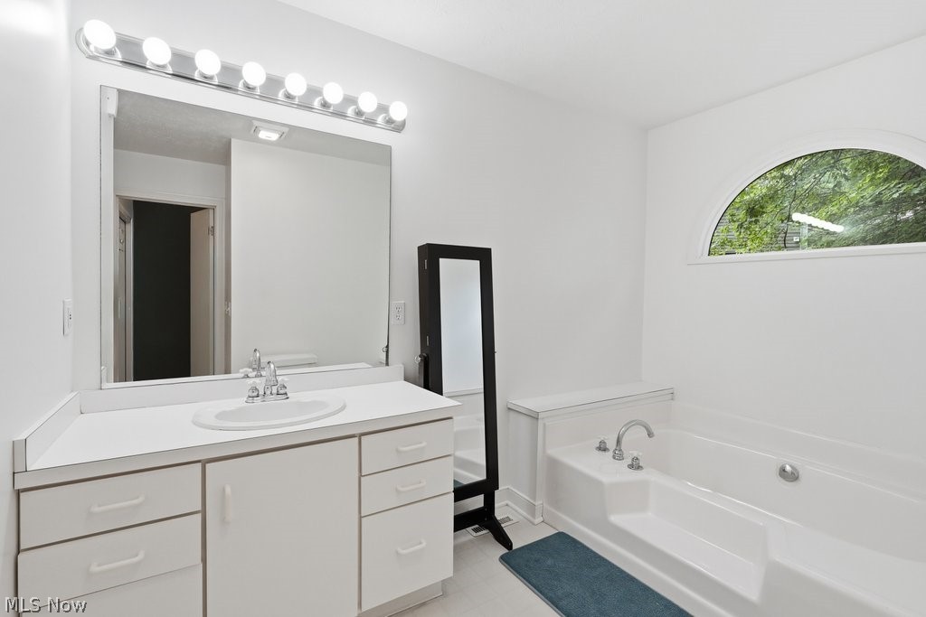 2323 Call Road Stow, OH 44224 - Photo 33 of 42 Ensuite Bathroom- featuring a built-in tub, arched window, and vanity with an integrated sink