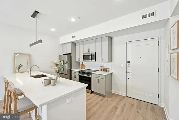 a kitchen with a sink a stove a refrigerator and white cabinets