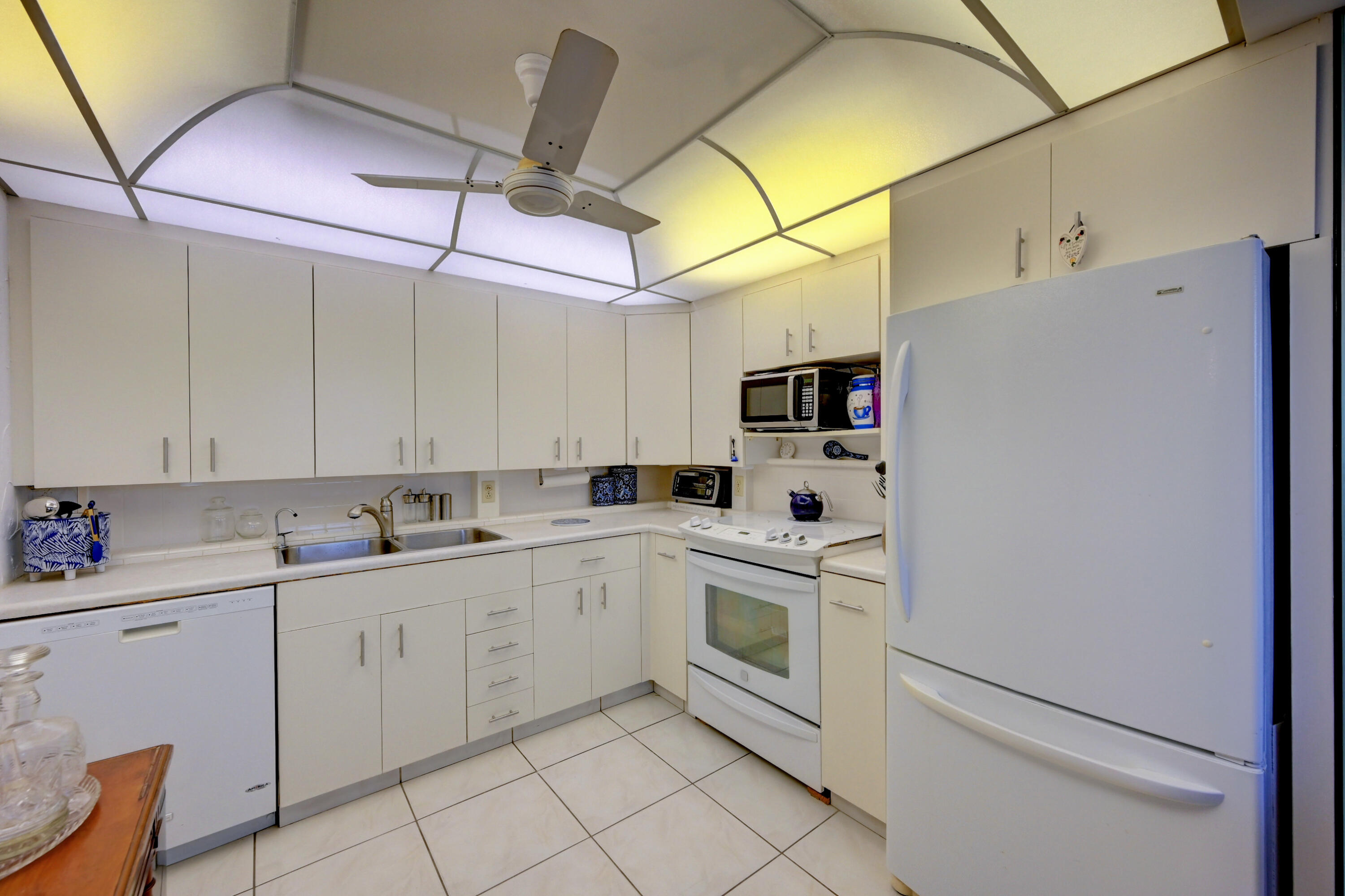2049 Newcastle A, Unit 2049 Boca Raton, FL 33434 - Photo 11 of 24 a kitchen with white cabinets and white appliances